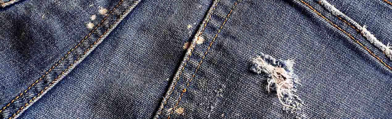 Close-up de tecido jeans rasgado com manchas
