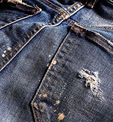 Close-up de tecido jeans rasgado com manchas